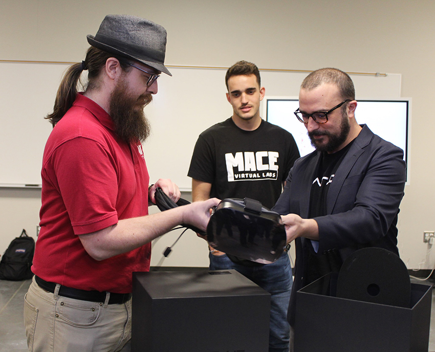 Three students look at a VR headset.
