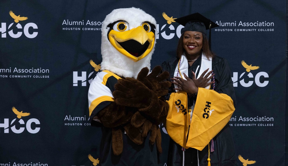 HCC Mascot Swoop and a student pose for a photo at the Fall Commencement Ceremony.