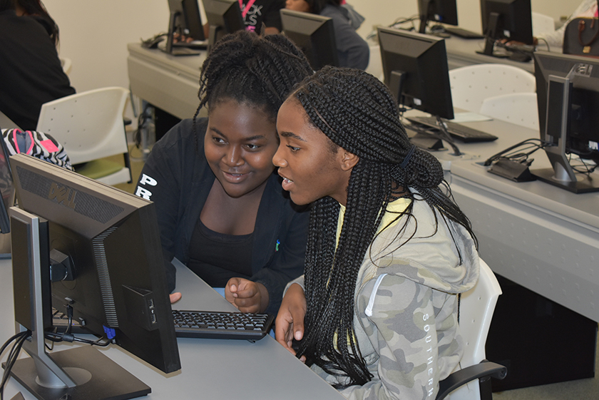 Students look at a computer screen at the Black Girls Code event