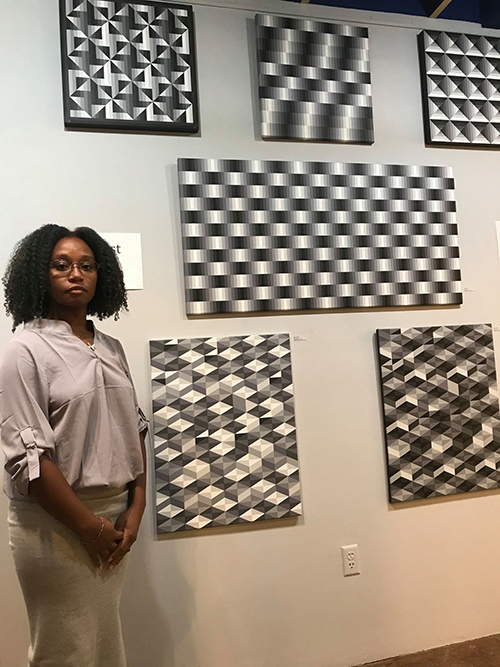 Kentra Gilbert poses for photo in front of art designs