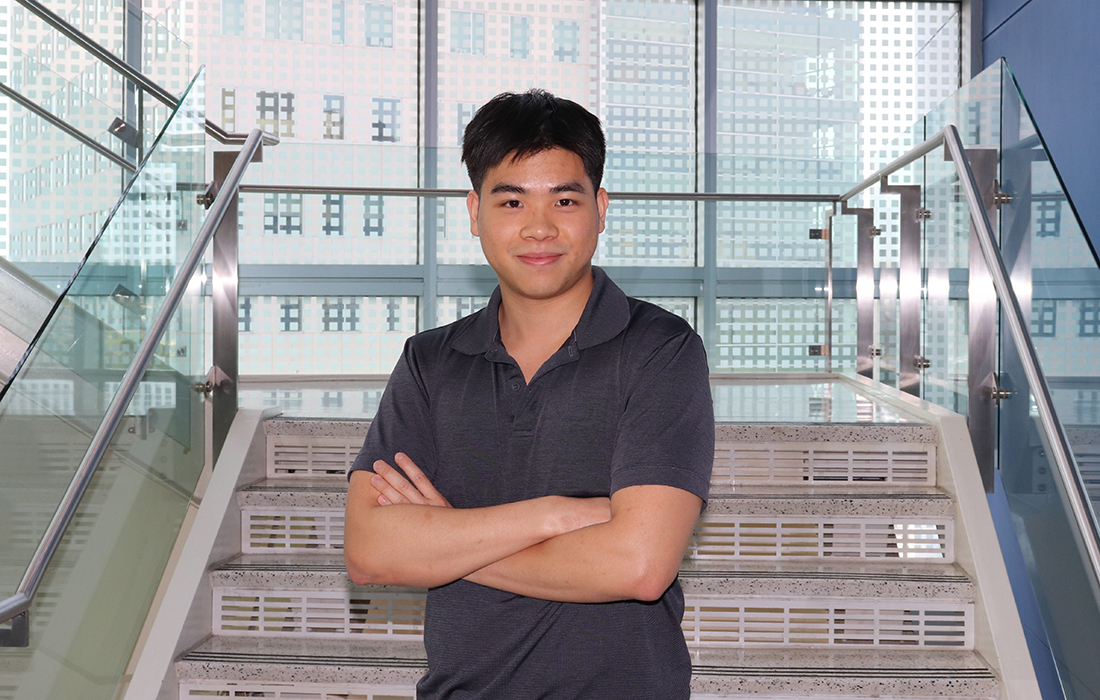 Minh Pham confidently stands in front of the staircase at HCC Coleman College