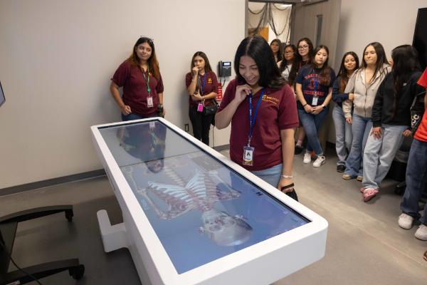 Students viewing a skeleton on a digital anatomage table